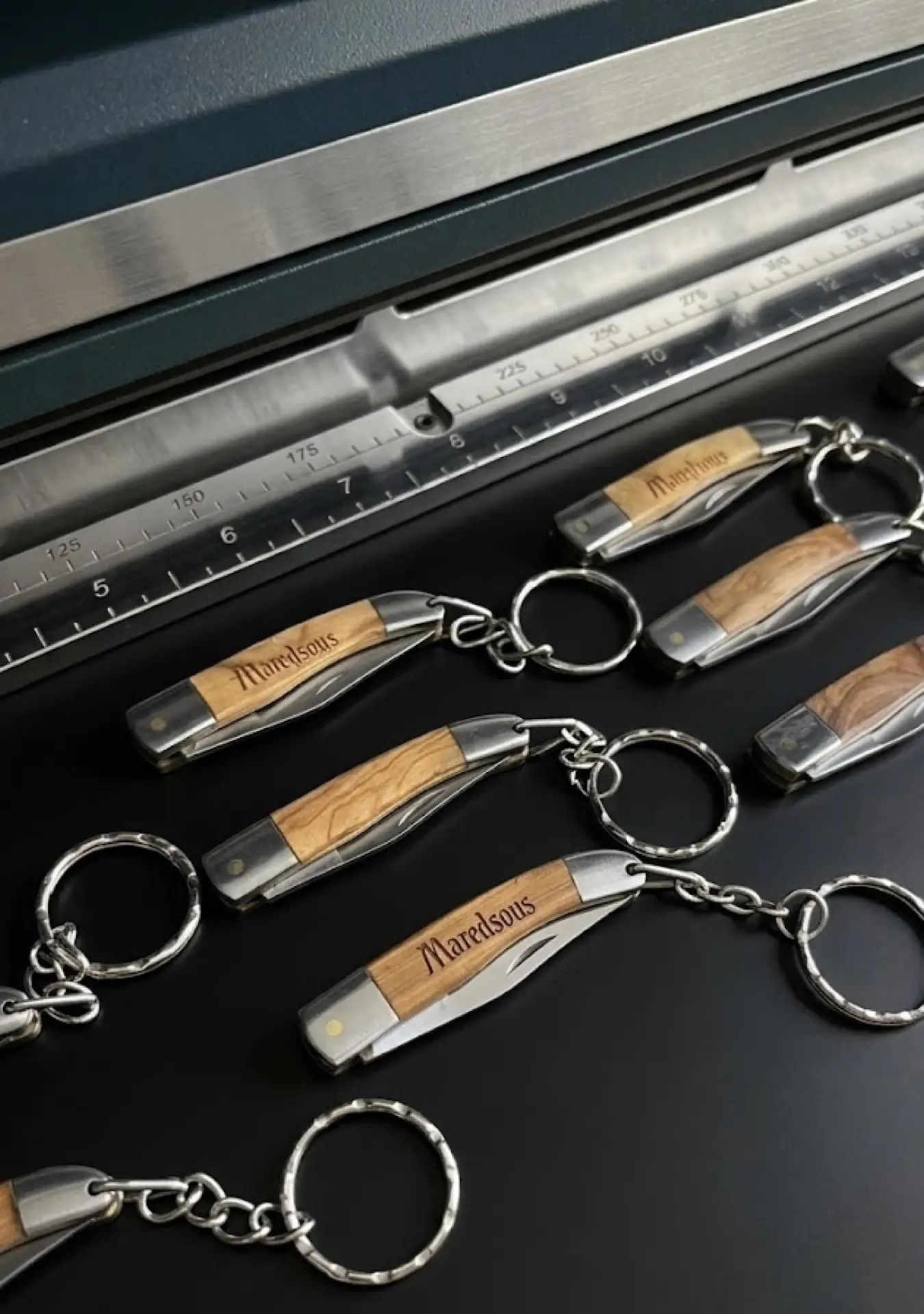 Porte-clés couteaux en bois d'olivier gravés au laser pour la boutique de l'abbaye de Maredsous