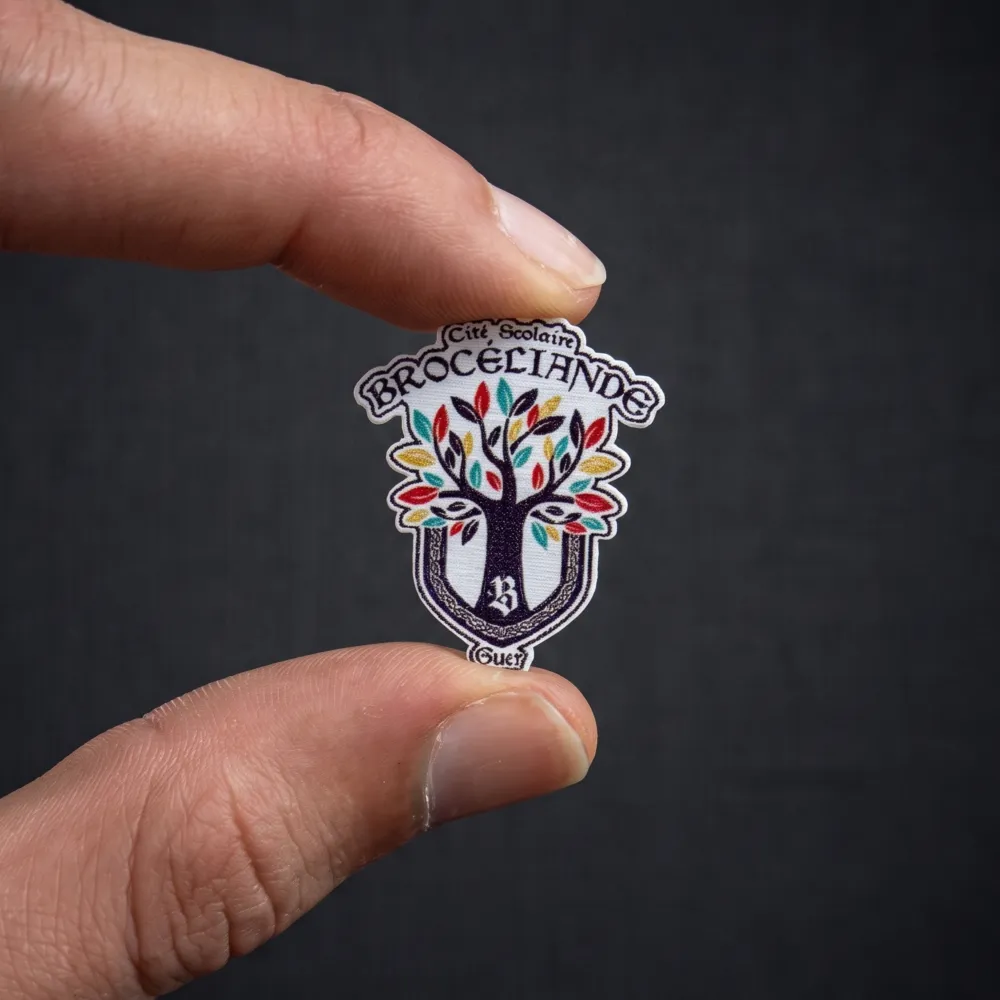 Pin's personnalisé tenu entre les doigts, fabriqué dans notre atelier en Anjou